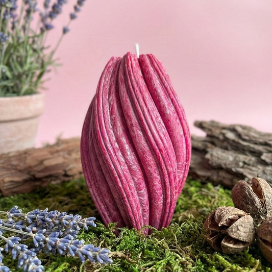 Pink textured candle on a natural background with lavender and stones